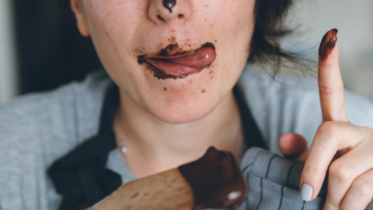 Close-up of a woman with chocolate on her lips, representing a strong chocolate craving and the struggle to cut down on chocolate.